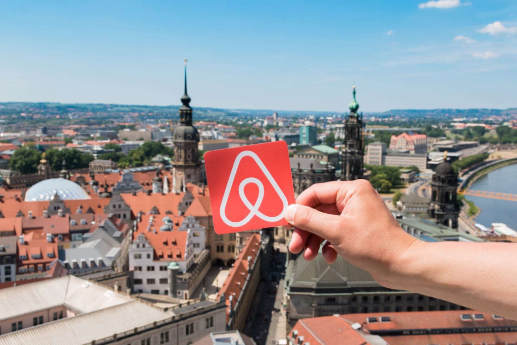 picture from a city in Europe along with a hand holding a paper with Airbnb's logo